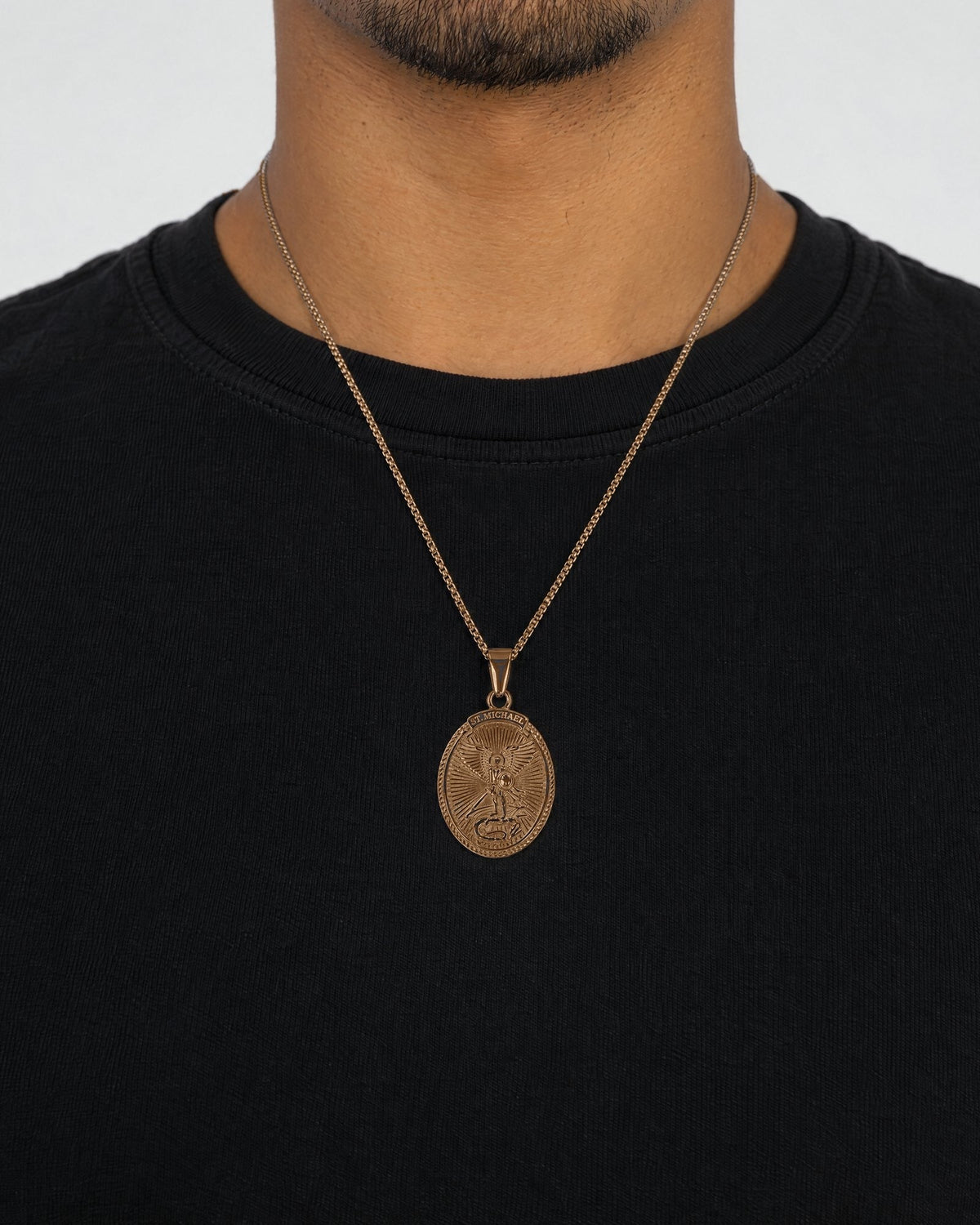 Mand i sort t-shirt med Archangel-vedhæng i guld, set forfra