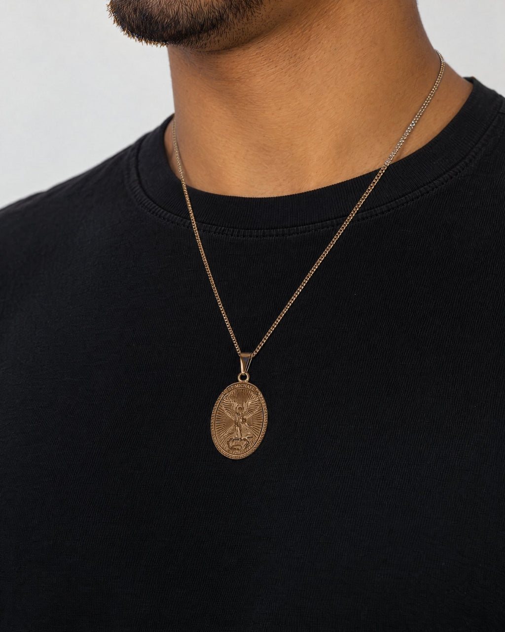 Mand i sort t-shirt med Archangel-vedhæng i guld, set fra siden