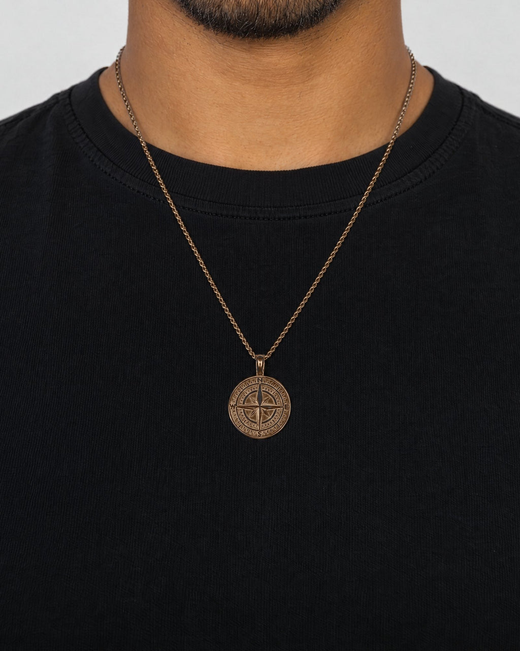 Mand i sort t-shirt med Compass-vedhæng i guld, set forfra
