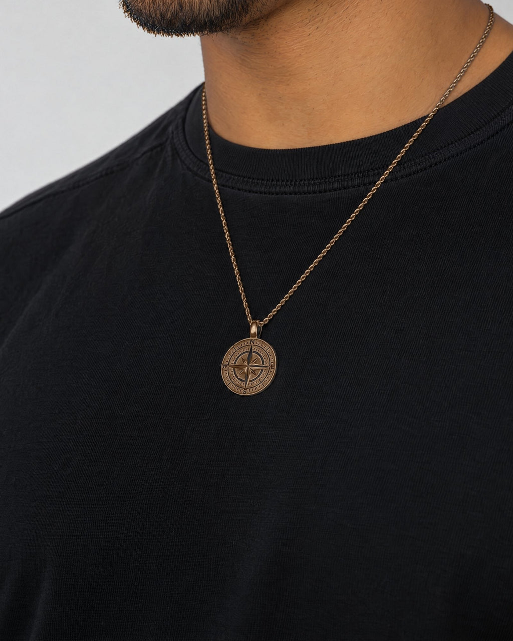 Mand i sort t-shirt med Compass-vedhæng i guld, set fra siden