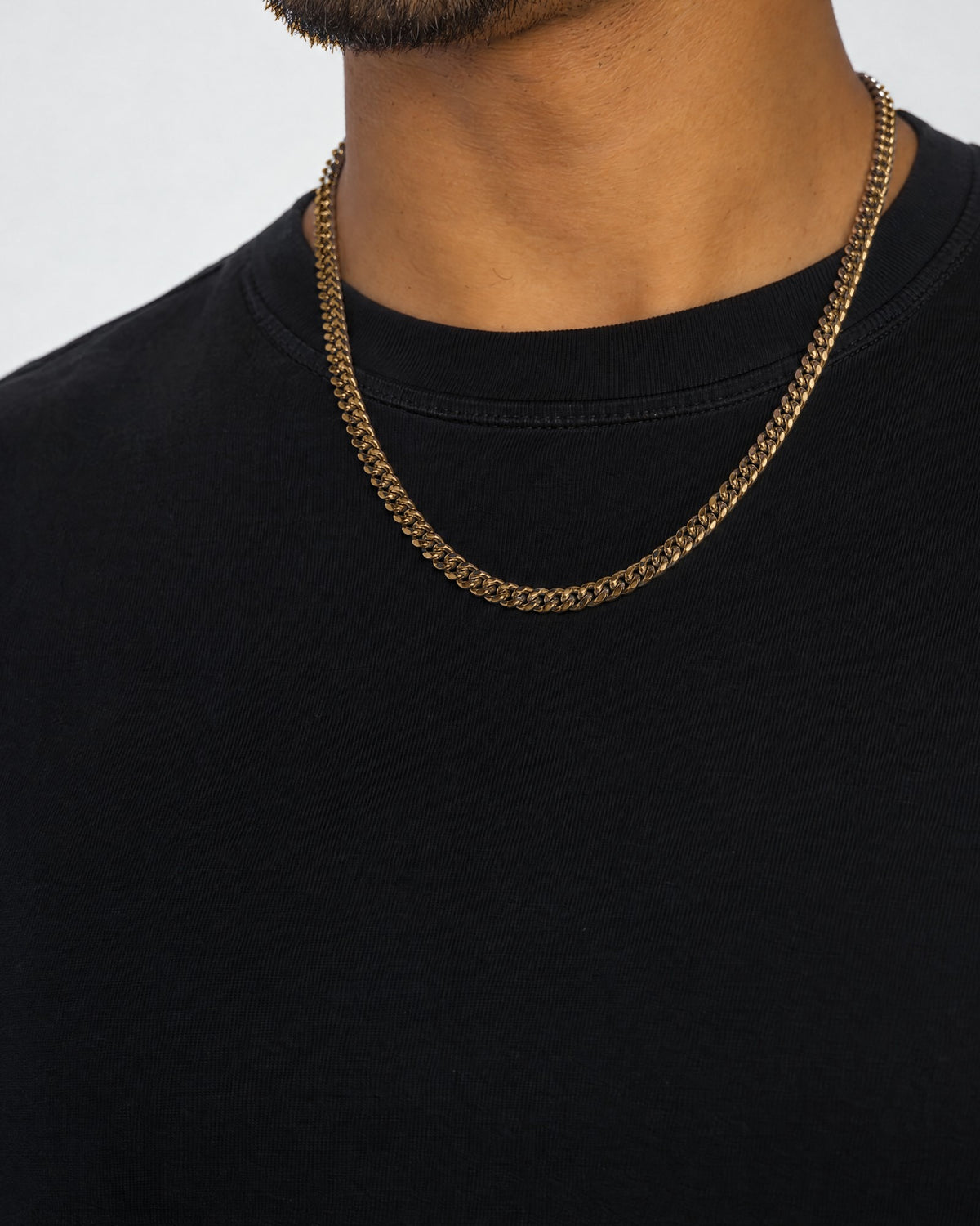 Mand i sort t-shirt med cuban-kæde i guld, set fra siden