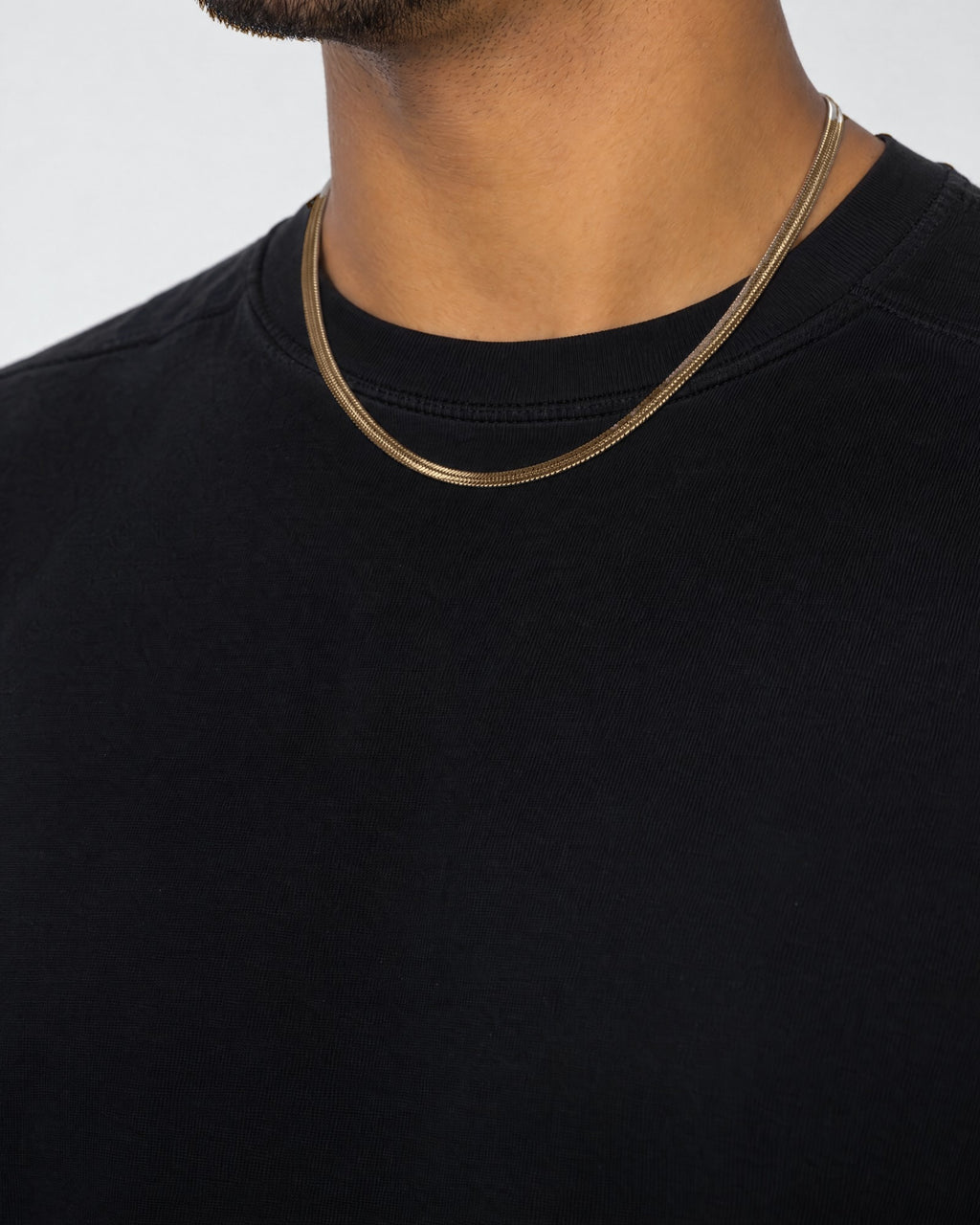 Mand i sort t-shirt med herringbone-kæde i guld, set fra siden