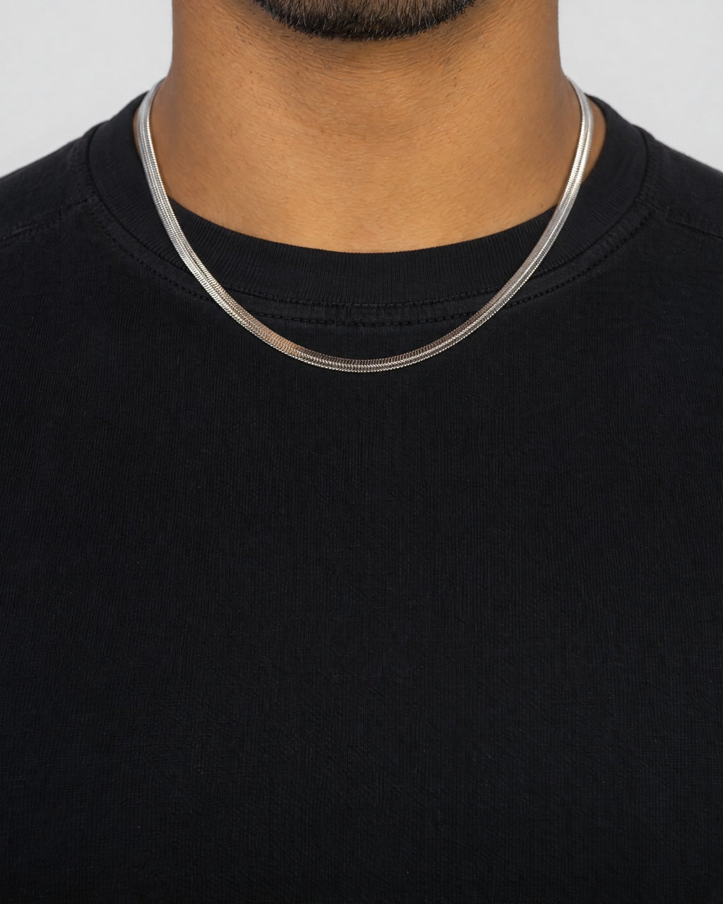 Mand i sort t-shirt med herringbone-kæde i sølv, set forfra