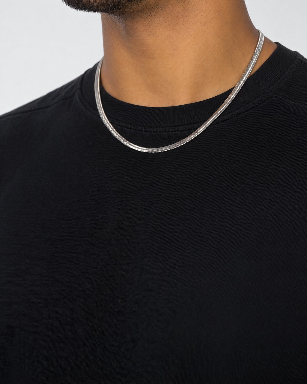 Mand i sort t-shirt med herringbone-kæde i sølv, set fra siden