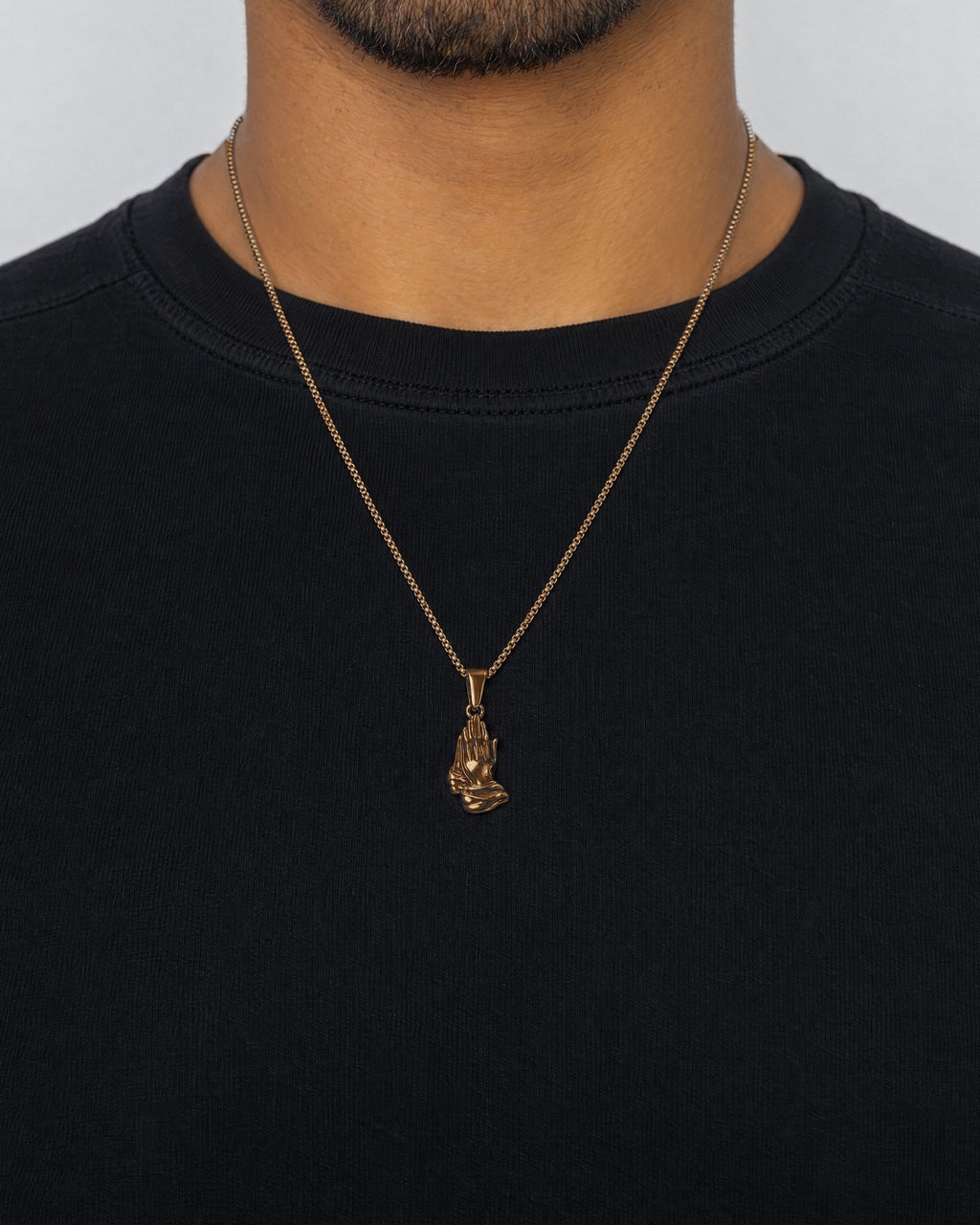 Mand i sort t-shirt med Praying Hands-vedhæng i guld, set forfra