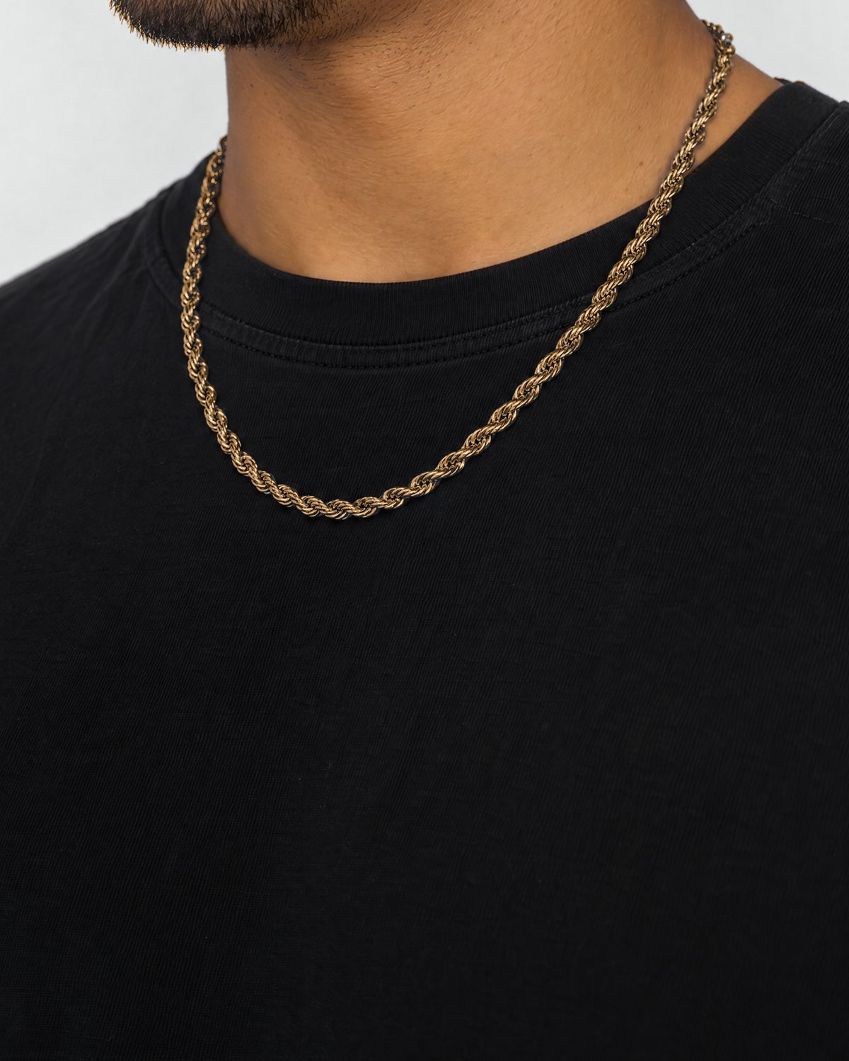 Mand i sort t-shirt med rope-kæde i guld, set fra siden