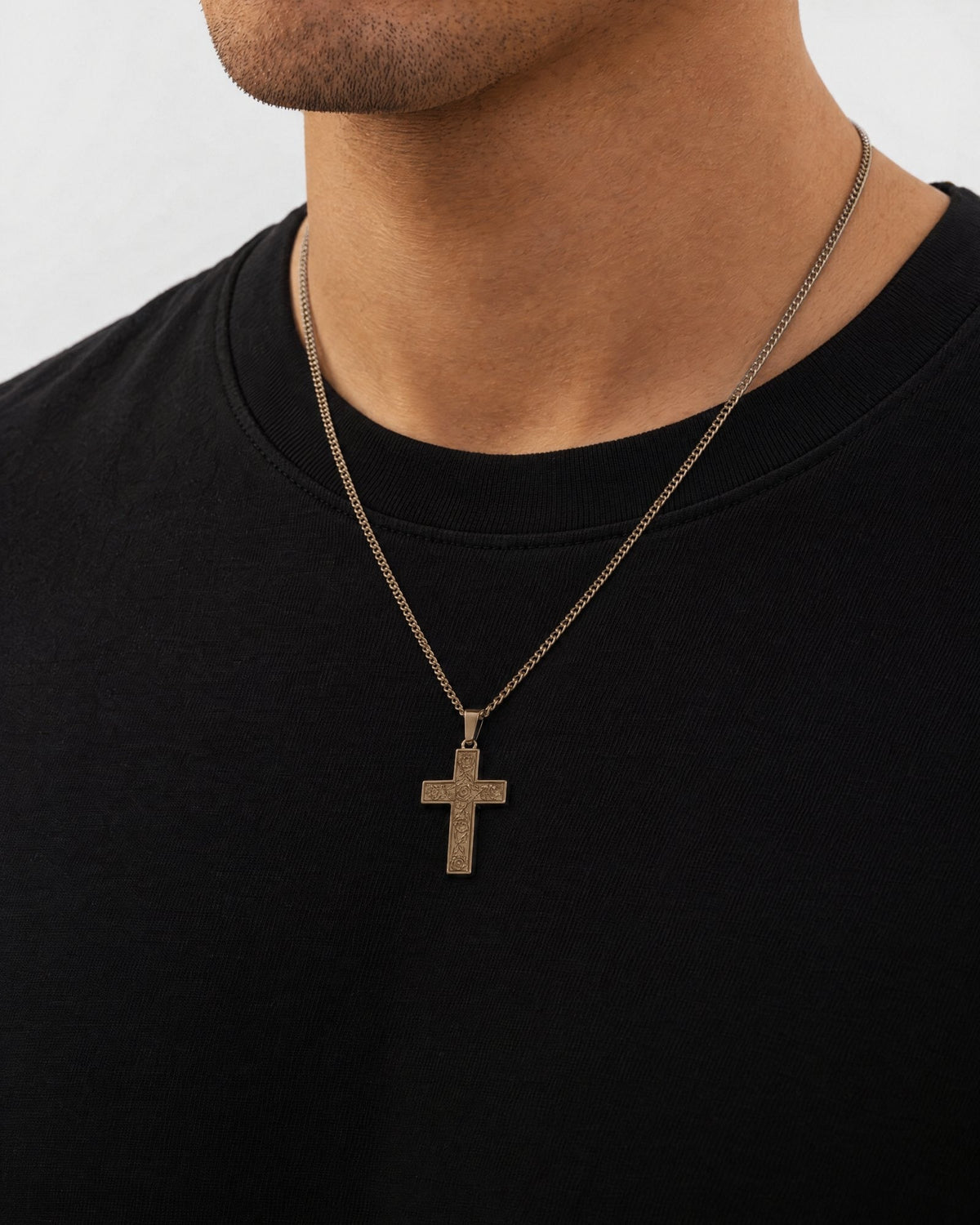 Mand i sort t-shirt med The Holy Cross-vedhæng i guld, set fra siden