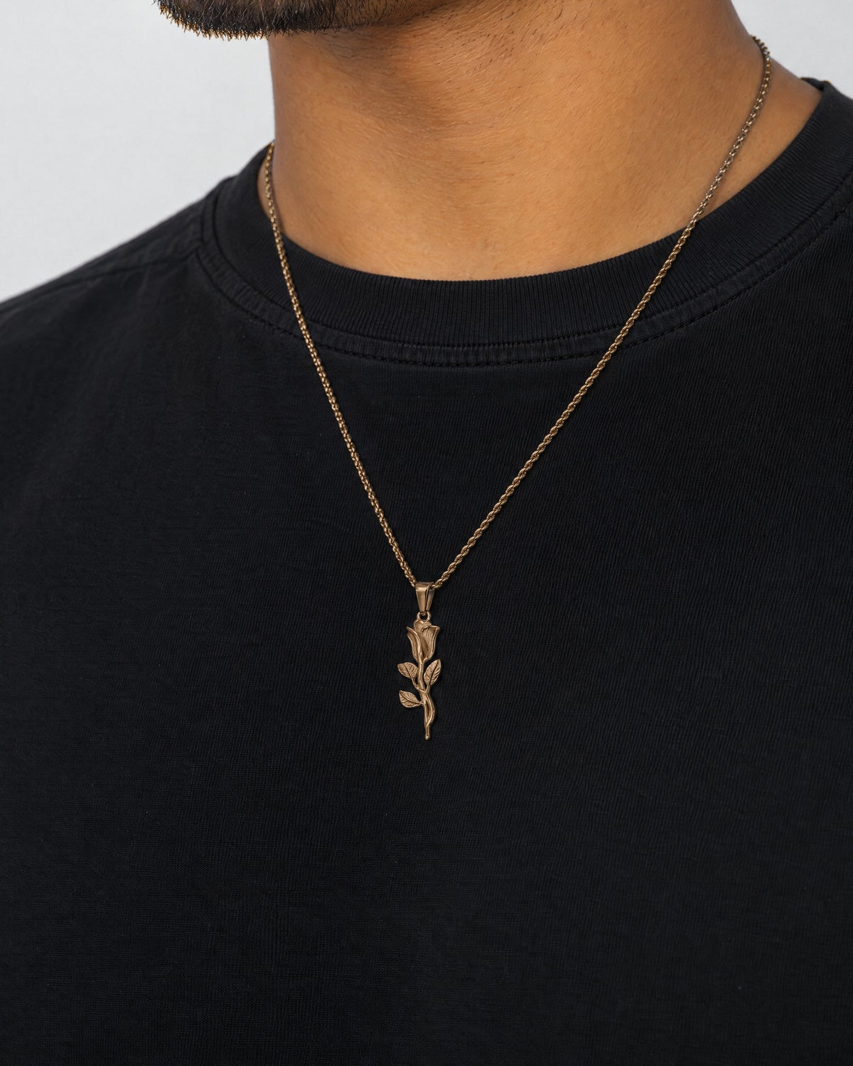 Mand i sort t-shirt med The Rose-vedhæng i guld, set fra siden