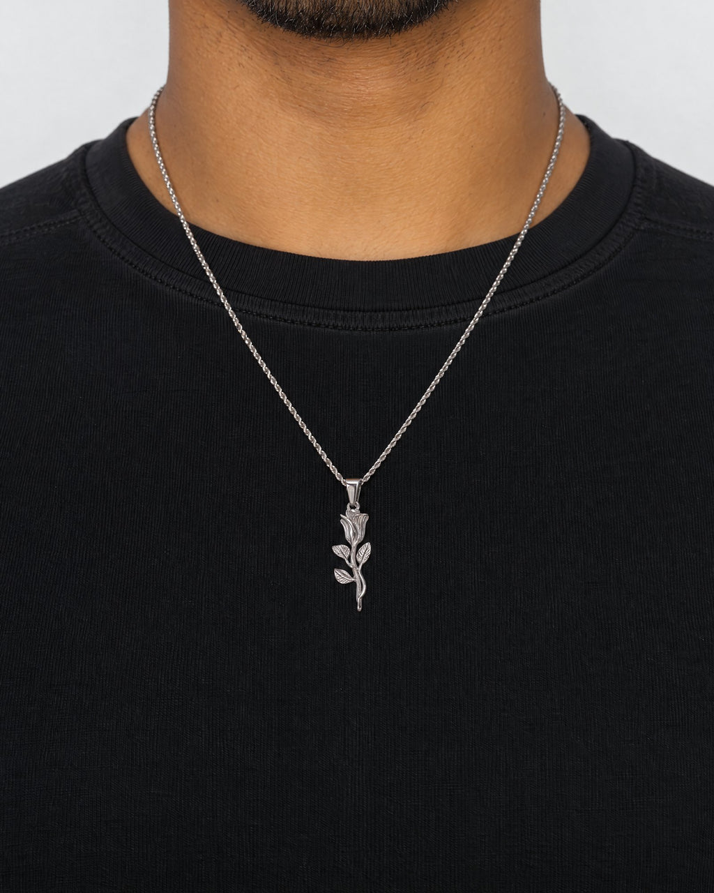 Mand i sort t-shirt med The Rose-vedhæng i sølv, set forfra