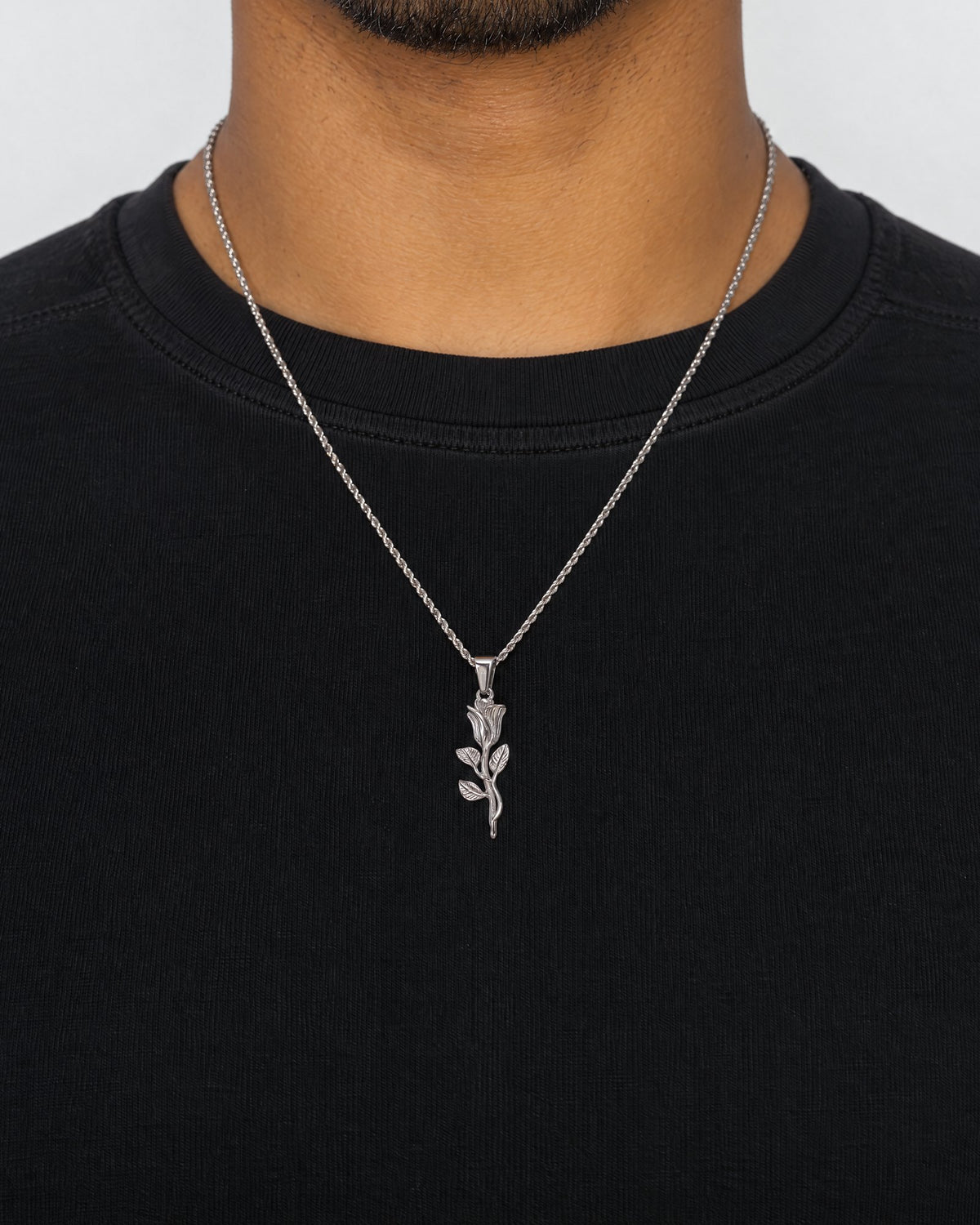 Mand i sort t-shirt med The Rose-vedhæng i sølv, set forfra