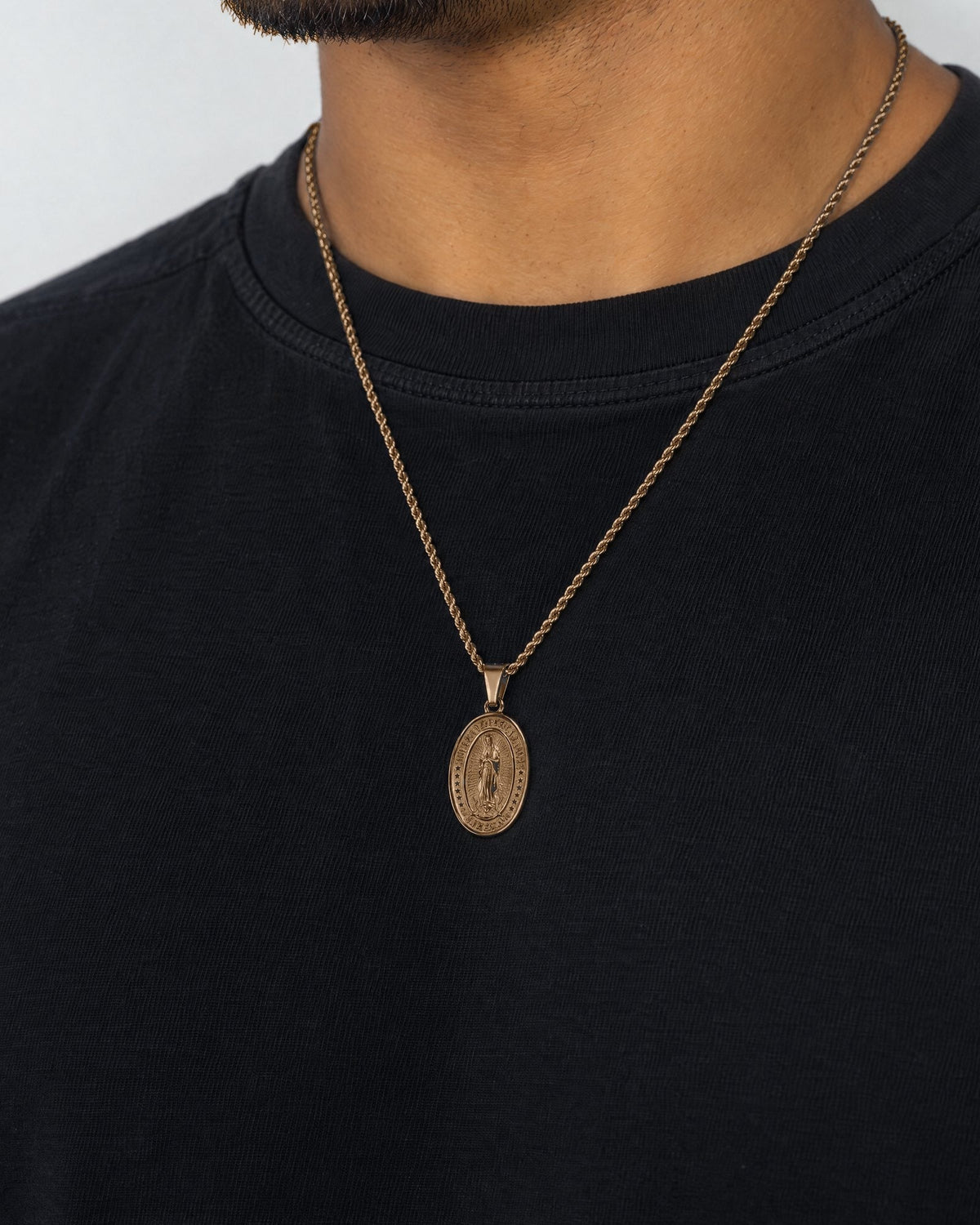 Mand i sort t-shirt med Virgin Mary-vedhæng i guld, set fra siden