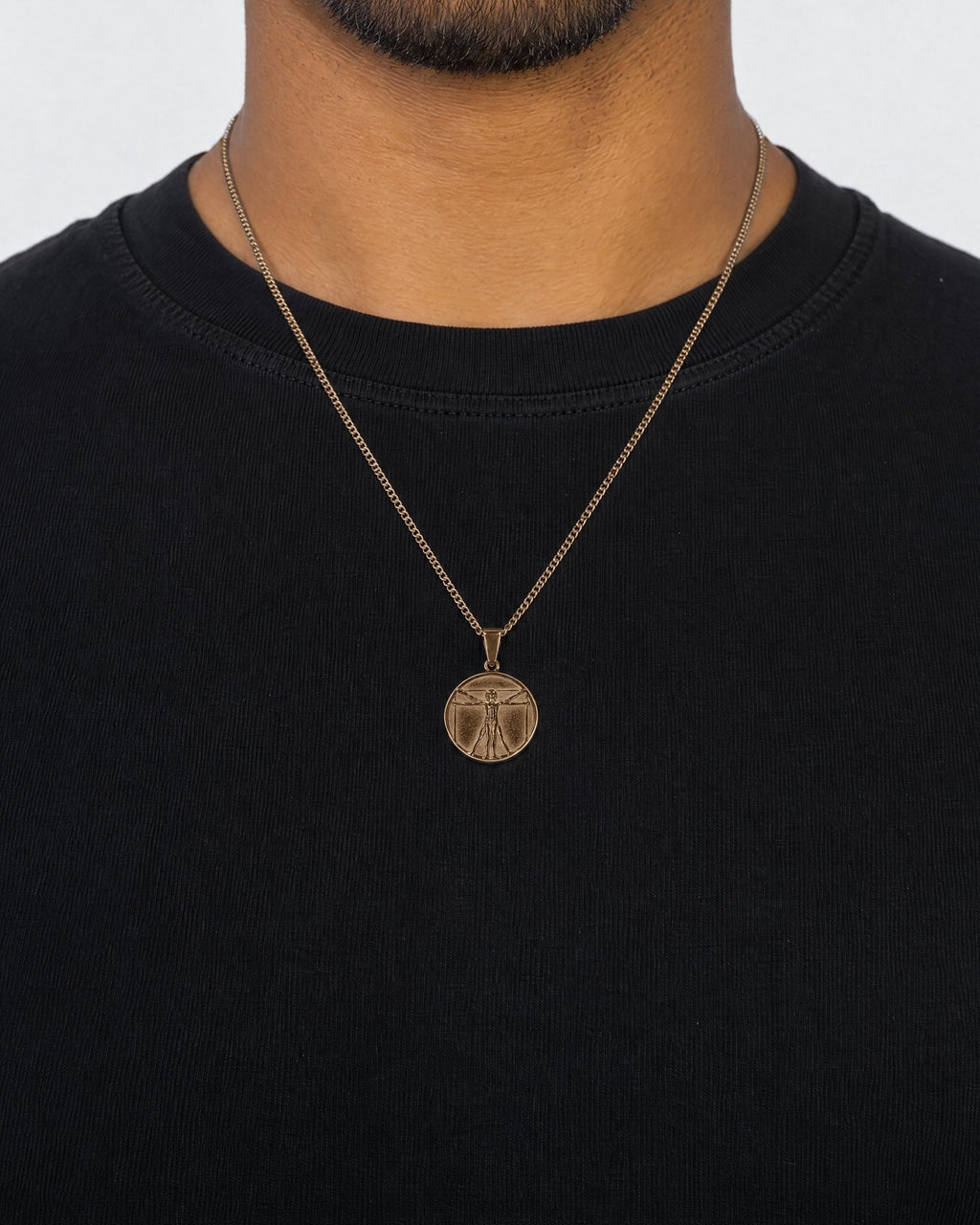 Mand i sort t-shirt med Vitruvian Man-vedhæng i guld, set forfra