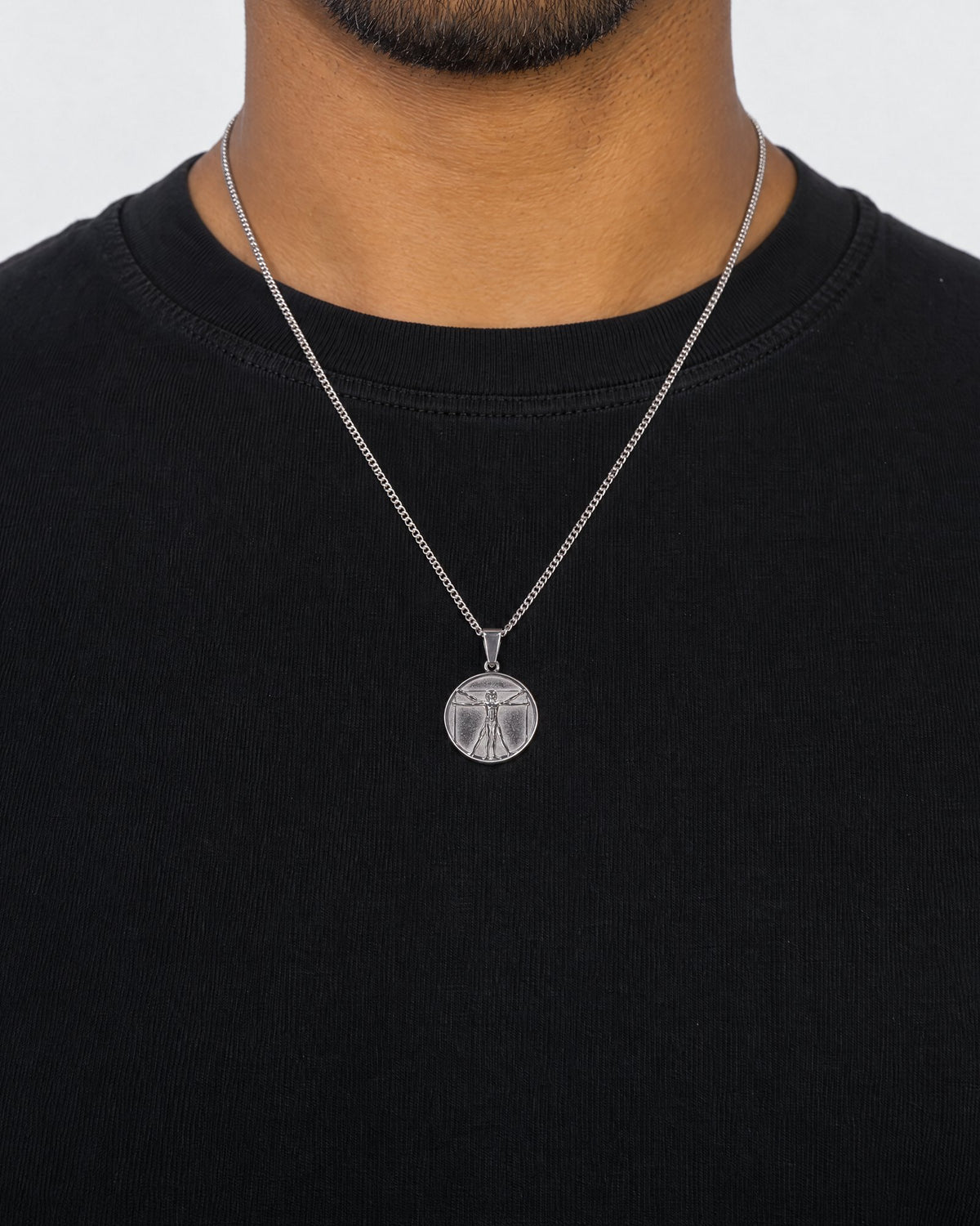 Mand i sort t-shirt med Vitruvian Man-vedhæng i sølv, set forfra