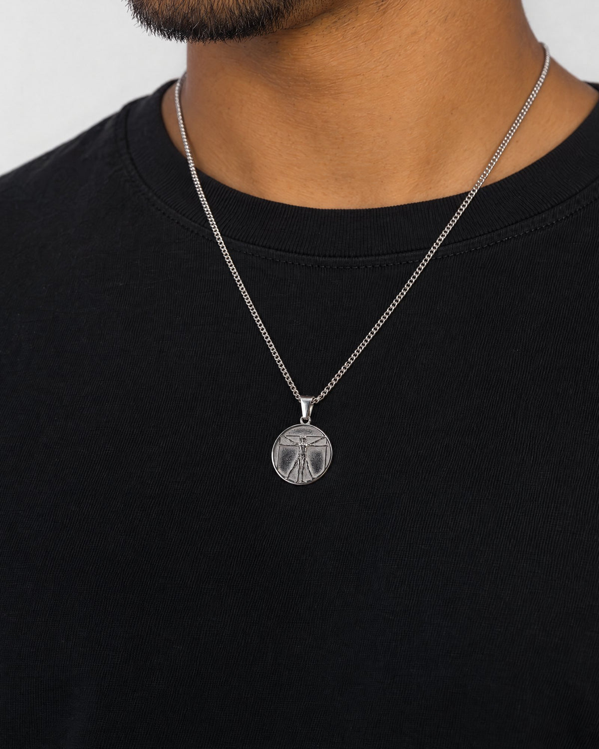 Mand i sort t-shirt med Vitruvian Man-vedhæng i sølv, set fra siden